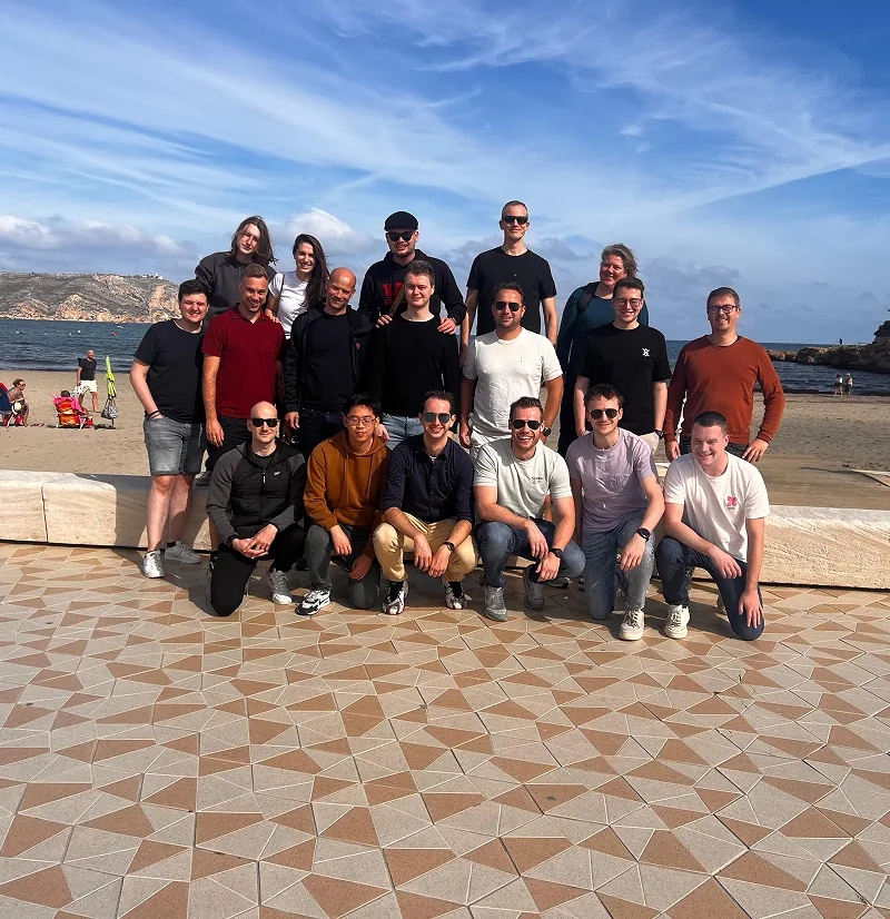 Groepsfoto van Twentecs-collega's op een boulevard aan het strand tijdens een teamuitje in Spanje