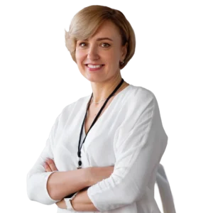 Vrouw met kort blond haar in witte blouse, armen over elkaar, voor een neutrale achtergrond