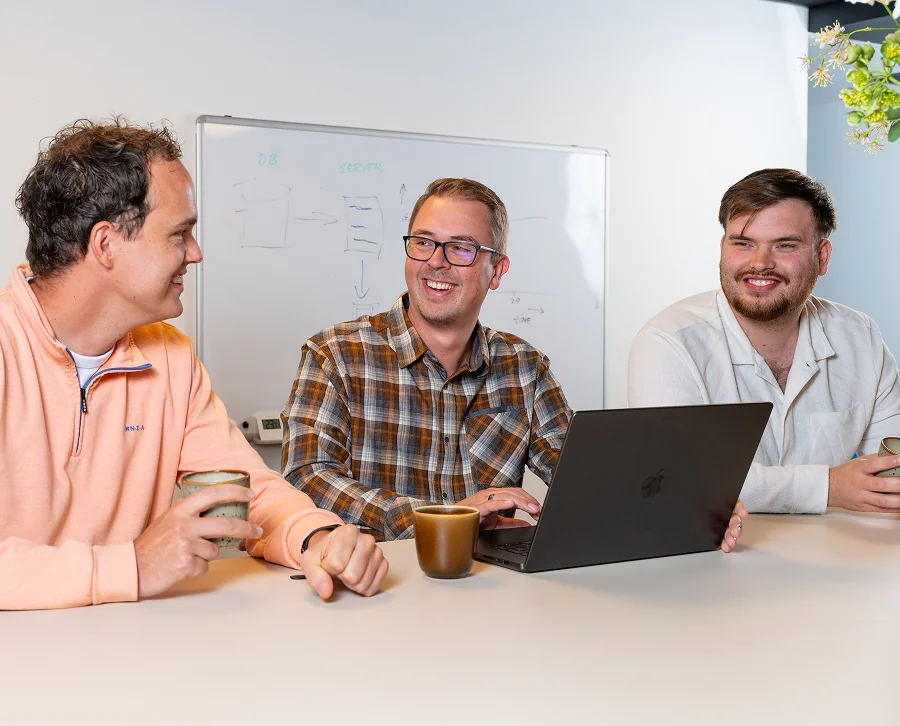 Drie collega's van Twentecs in gesprek aan tafel met een laptop