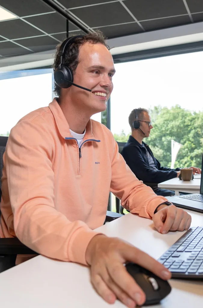 Medewerker van Twentecs met headset achter een laptop op kantoor