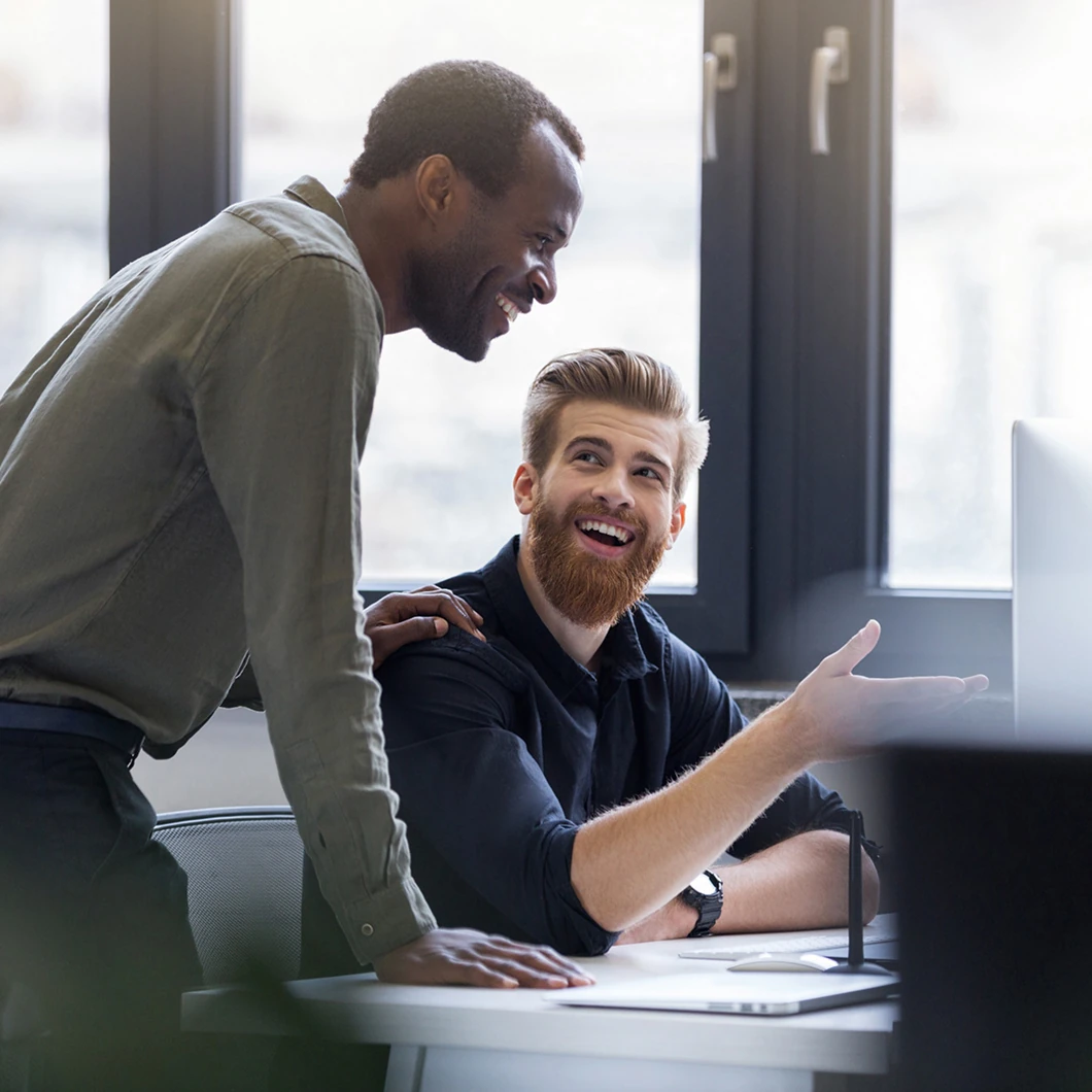 Twee collega's in gesprek bij een computer, klantverhaal Randstad