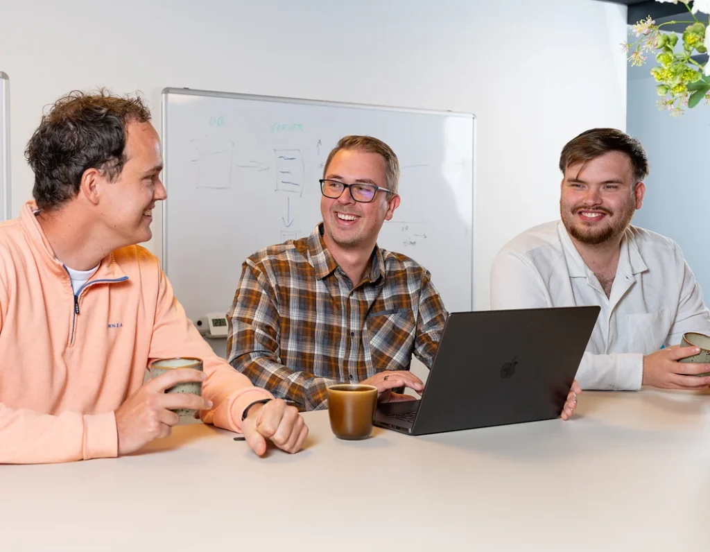 Drie collega's van Twentecs lachend rond een laptop