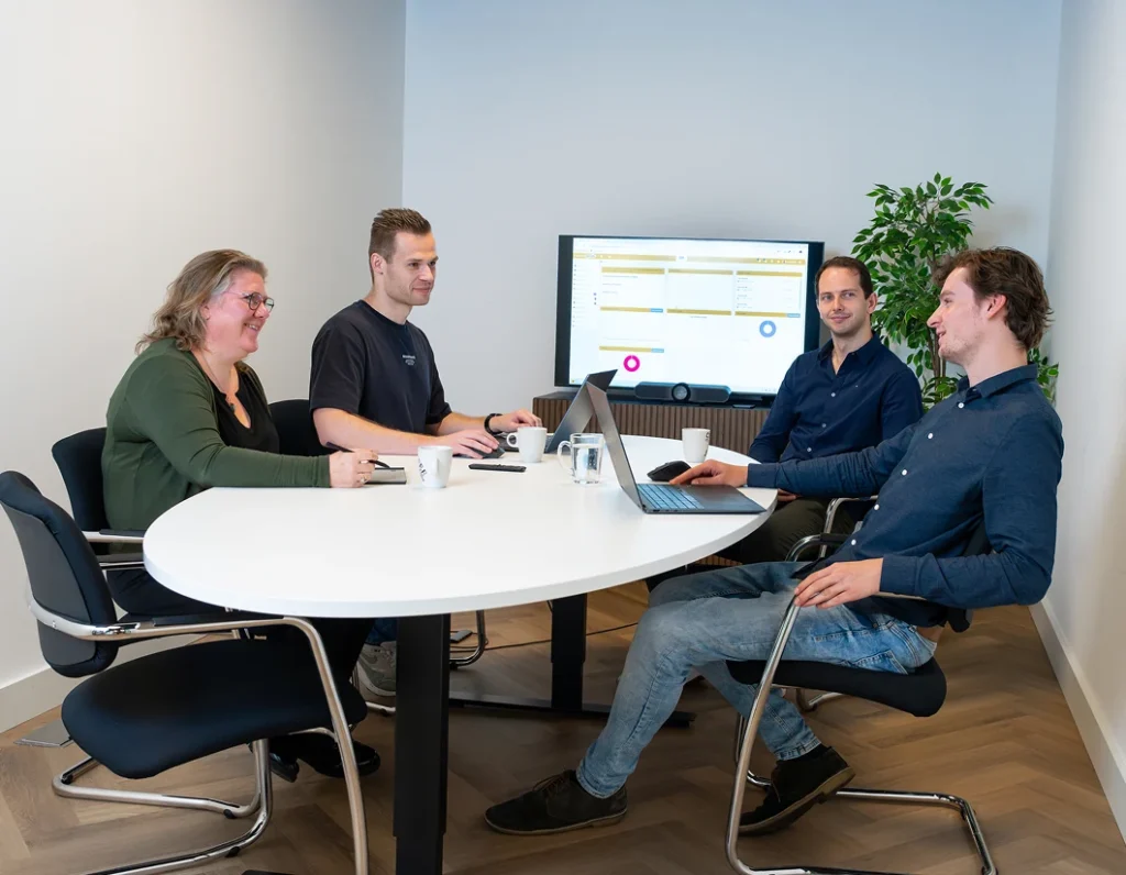 Vier collega's van Twentecs in een vergadering met een dashboard op het scherm.