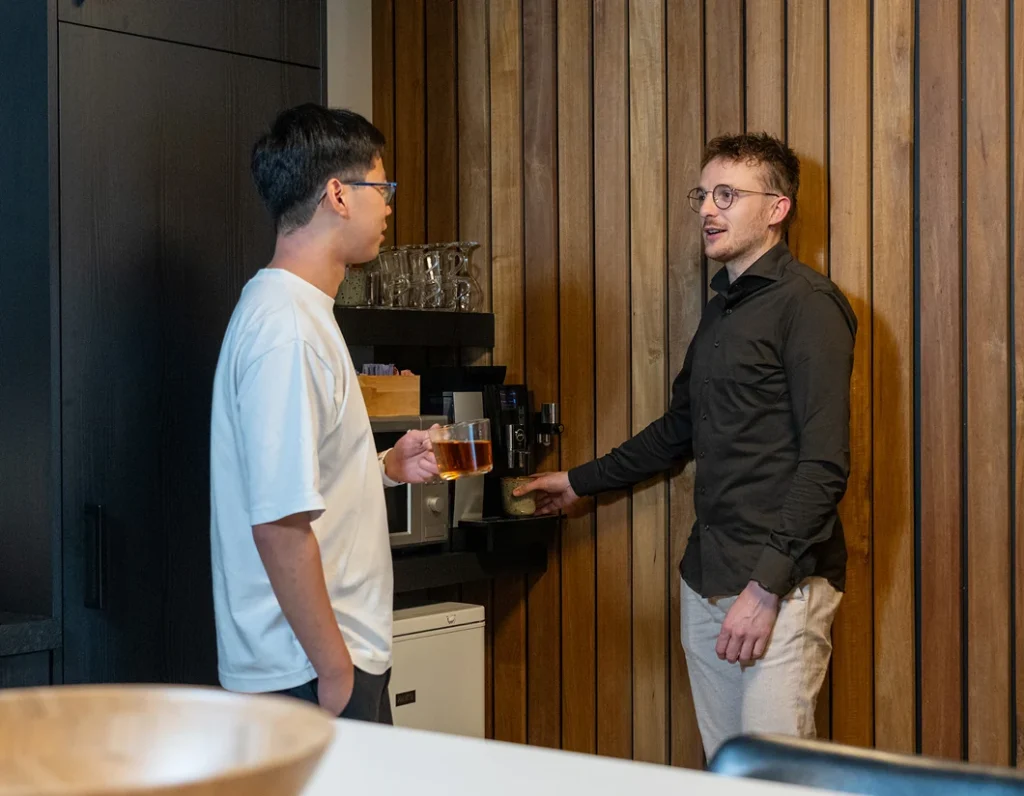 Twee collega's van Twentecs bij het koffieapparaat tijdens een informeel gesprek.