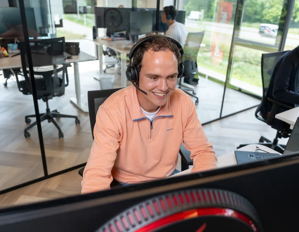 Medewerker met headset achter een computerscherm in het Twentecs-kantoor.