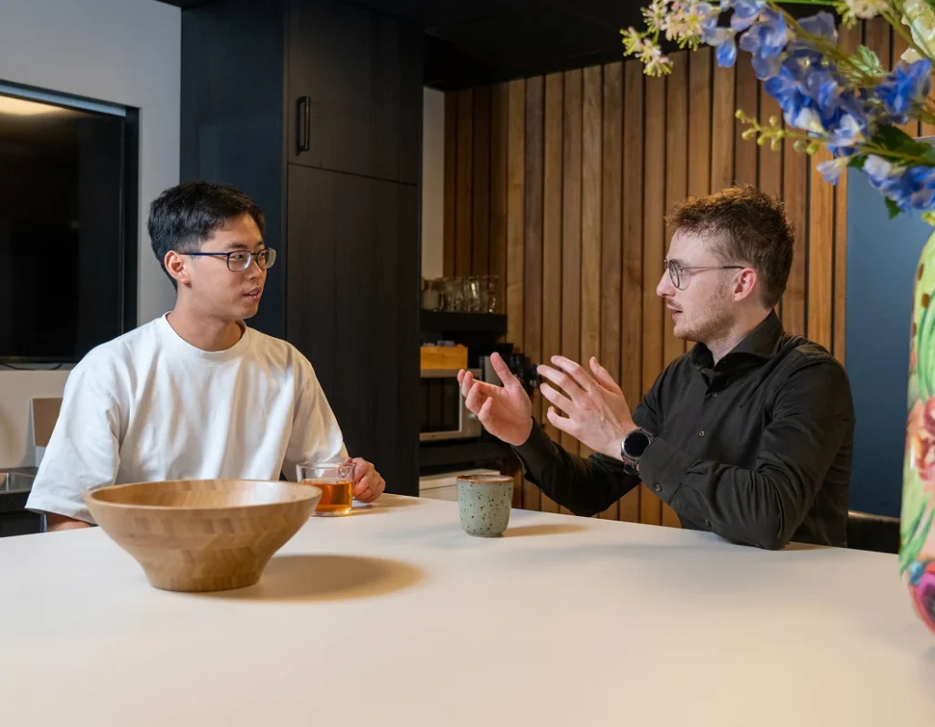 Twee collega's van Twentecs in gesprek aan tafel met thee en koffie.