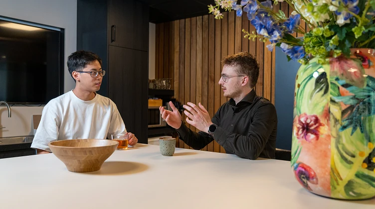 Twee collega's van Twentecs in gesprek aan tafel met thee en koffie.