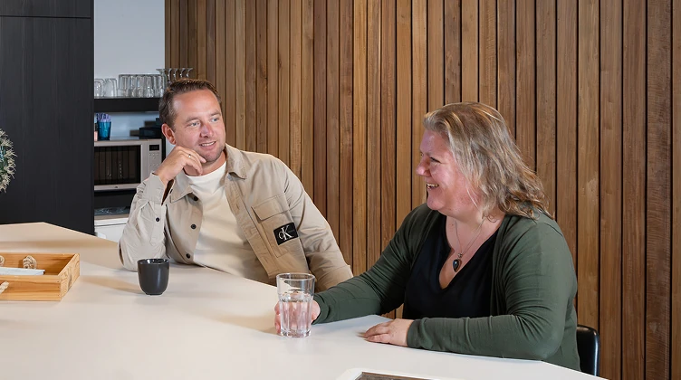 Man en vrouw van Twentecs in gesprek aan tafel met een teabox.