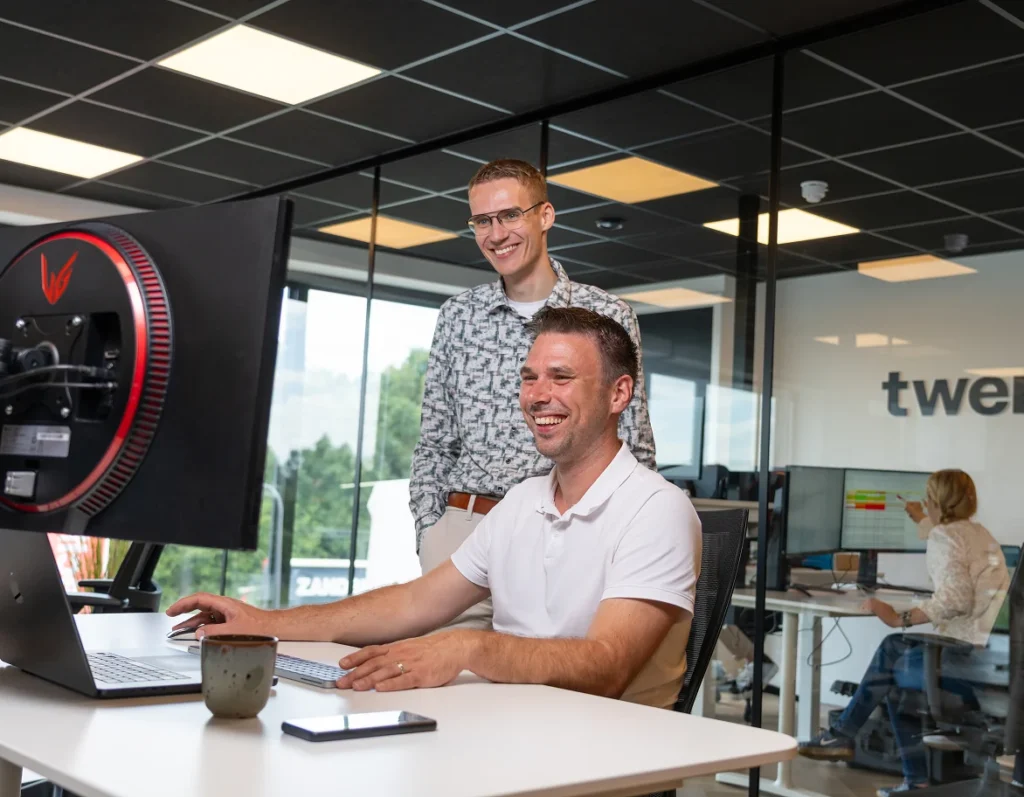 Twee collega's van Twentecs achter een computerscherm op kantoor