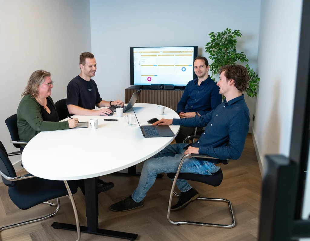 Vier collega's van Twentecs in overleg met een scherm op de achtergrond