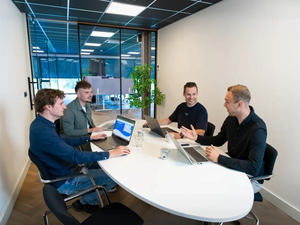 Vier collega's van Twentecs in overleg aan een tafel met laptops in een vergaderruimte