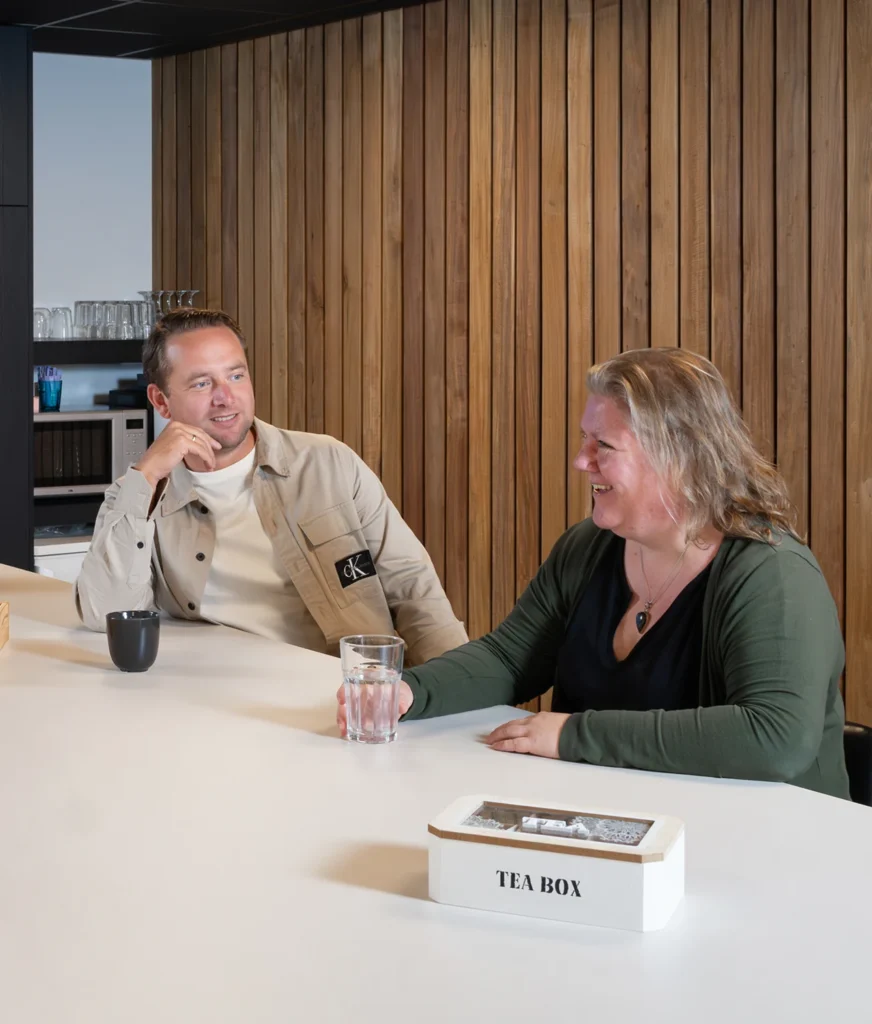 Twee collega's van Twentecs in gesprek aan de bartafel.