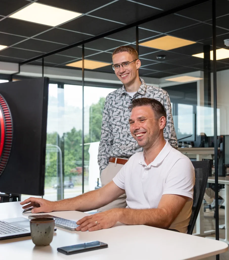 Twee collega's van Twentecs achter een beeldscherm op kantoor.