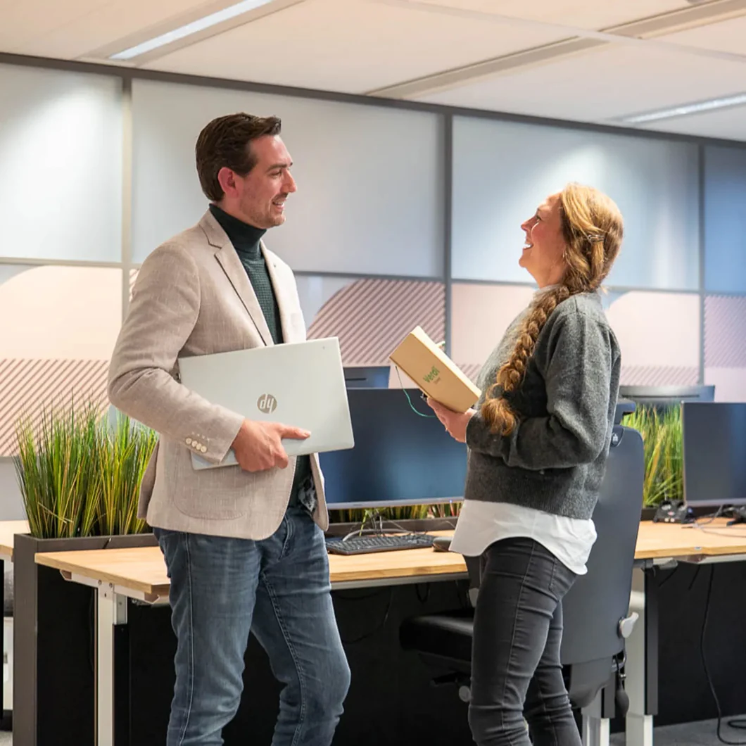 Twee collega's lachen samen op kantoor, klantverhaal Verdi Groep